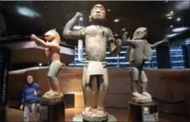  ?? MICHEL EULER — THE ASSOCIATED PRESS ?? A visitors look at wooden royal statues of the Dahomey kingdom, dated 19th century, today’s Benin,at Quai Branly museum in Paris, France, Friday.