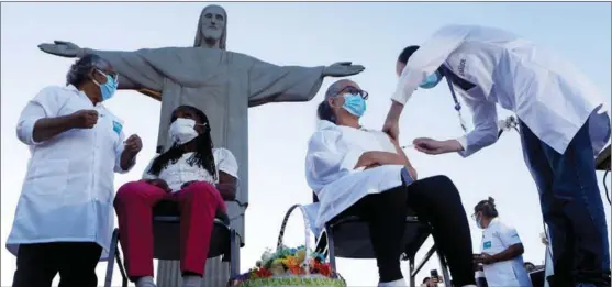  ?? BRUNA PRADO / AP ?? Terezinha da Conceicao (left) and Dulcinea da Silva Lopes are among the first to receive the COVID-19 vaccine produced by China’s Sinovac Biotech during the start of the vaccinatio­n program in front of the Christ the Redeemer statue in Rio de Janeiro, Brazil, on Jan 18.