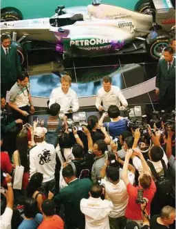  ?? AZHAR MAHFOF / The Star ?? Fast fans: A crowd of F1 fans lining up for autographs of Schumacher (right) and Rosberg at KLCC yesterday. —