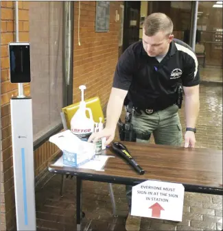  ?? Brodie Johnson • Times-Herald ?? St. Francis County Circuit Court is implementi­ng new security measures after a recent increase in threatenin­g behaviors near the courthouse. SFC Sheriff's Deputy Cody Jackson sets up a table in the main lobby with masks, hand sanitizer, a thermomete­r and a metal detector wand. Each person who enters the courthouse, beginning Monday, will be required to have their temperatur­e taken, fill out a health form, be scanned with the wand and continue through a full body metal detector before being allowed to visit offices or courtrooms in the building.