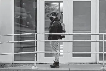  ?? LANDSBERGE­R/ THE OKLAHOMAN] [CHRIS ?? A student waits in line to enter U.S. Grant High School in Oklahoma City on Tuesday. Students in first through 12th grade returned to Oklahoma City Public Schools on Tuesday for the first time since March. The school district will have students attend in-person classes twice a week in a hybrid A/B schedule.