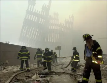  ?? AP Photo/MArk LennIhAn ?? In this 2001 file photo, with the skeleton of the World Trade Center twin towers in the background, New York City firefighte­rs work amid debris on Cortlandt Street. after the terrorist attacks.