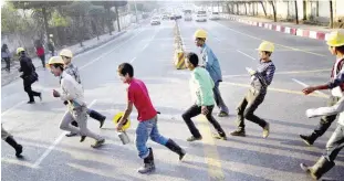  ??  ?? YANGON: Constructi­on workers cross a main road to reach a building site in Yangon yesterday. Unskilled constructi­on workers make more than Myanmar’s set a minimum wage of 3,600 kyat ($2.75) for an eighthour workday, as the country’s constructi­on...