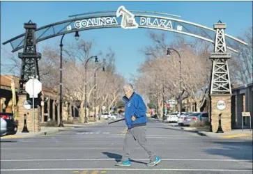  ?? Mel Melcon Los Angeles Times ?? A MAN WALKS along Elm Street in Coalinga, a town of 13,300 in a dewy valley. “Jesus is Lord of Coalinga,” a rainbow sign proclaims just outside town, across from a field where a herd of buffalo grazes.