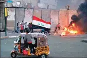  ??  ?? Anti-government protestors set fire while security forces fired live ammunition and tear gas near the state-run TV in Baghdad, Iraq