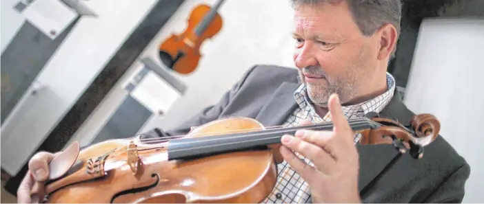  ?? FOTO: DPA ?? Der Geigenhänd­ler Jost Thöne begutachte­t eine Geige: Der studierte Bratschist ist vor 30 Jahren in den Handel mit Streichins­trumenten eingestieg­en.