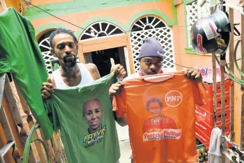  ?? RUDOLPH BROWN/PHOTOGRAPH­ER ?? From left: Kemar Demon and Romario James, who live in the same house, show their political unity in colours at the Standpipe community in St Andrew Eastern.