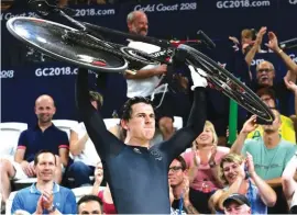  ?? Photo: AP ?? New Zealand’s Sam Webster lifts his bicycle after winning gold at the Men’s Sprint