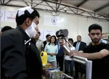  ??  ?? U.S. Ambassador to the United Nations Nikki Haley (background center) looks on as a bandaged Syrian refugee has his iris scanned at a supermarke­t Sunday in Zaatari Refugee Camp, Jordan. AP PHOTO