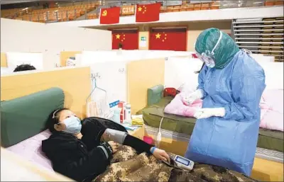  ?? EPA/Shuttersto­ck ?? A MEDICAL WORKER attends to a patient in a makeshift hospital establishe­d to treat COVID-19 in Wuhan, China.