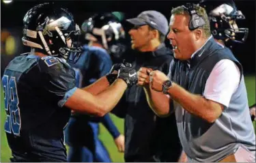  ?? MARK C PSORAS--THE REPORTER ?? North Penn Head Coach Dick Beck gives a fist bump to Justin Ostopowicz ,30, after a Knights touchdown against Souderton during first half action of their contest at North Penn High School on Friday October 9,2015.