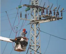  ?? AFP ?? Palestinia­n workers repair power lines on the eastern outskirts of Gaza City, which reportedly enjoys about 200 megawatts of electricit­y a day now.