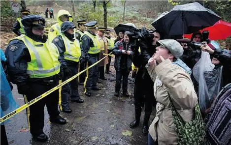  ?? DARRYL DYCK/THE CANADIAN PRESS ?? RCMP officers block the road on Burnaby Mountain in November while Kinder Morgan prepares for pipeline expansion.