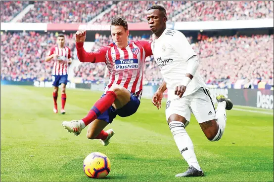  ?? (AP) ?? Real Madrid’s Vinicius Junior (right), is tackled by Atletico Madrid’s Santiago Arias during a Spanish La Liga soccer match between Atletico Madrid and Real Madrid at the Metropolit­ano Stadiumin Madrid, Spain on Feb 9.