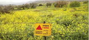  ?? (Ronen Zvulun/Reuters) ?? A CAUTION sign for land mines is seen on a fence in the Golan Heights.