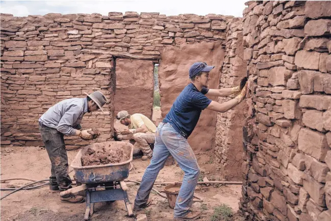  ?? ROBERTO E. ROSALES/JOURNAL ?? From left, Park Ranger Patrick Romero, Garrett Green and Victor Zamora grab handfuls of mud and press it between the stones to stabilize the walls of a historic structure beside the San Gregorio Mission church. Romero started doing this work during the...