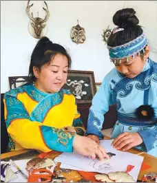  ?? ZHOU HUIYING / CHINA DAILY ?? A local elementary school student learns to make fish-skin paintings from a teacher of Hezhe ethnic folk arts in Zhuaji village in Fuyuan, Heilongjia­ng province, last month.