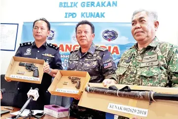  ??  ?? Hazani, Jauteh and Md Rahim shwoing the guns and samurai sword seized from the kidnapping suspects.