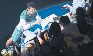  ?? QUINN ROONEY GETTY IMAGES ?? Novak Djokovic signs his autograph for fans after winning his Men’s Singles Final match against Daniil Medvedev at the Australian Open at Melbourne Park on Sunday.