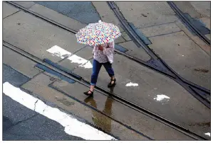  ?? (Arkansas Democrat-Gazette/Thomas Metthe) ?? A woman huddles under her umbrella Tuesday in Little Rock as she crosses River Market Avenue in the rain.