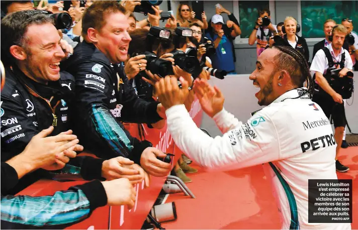  ?? PHOTO AFP ?? Lewis Hamilton s’est empressé de célébrer sa victoire avec les membres de son équipe dès son arrivée aux puits.