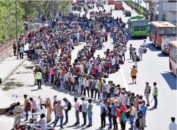  ?? — G.N. JHA ?? Migrants queue up to board buses to their native villages at Anand Vihar ISBT in New Delhi on Saturday. Scores of migrant workers continued to leave Delhi-NCR on Friday, the third day of the nationwide lockdown announced by Prime Minister Narendra Modi earlier this week.