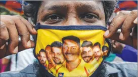  ??  ?? A man shows his facemask decorated with portraits of Chennai Super Kings cricket captain Mahendra Singh Dhoni (centre) and other team players as Covid-19 coronaviru­s cases continue to rise in the country