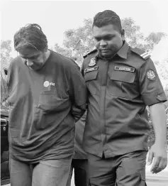  ??  ?? Camacho (left) being escorted by Customs Department personnel at the Magistrate’s Court. — Bernama photo