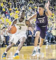  ?? Tony Ding / Associated Press ?? Michigan guard Zavier Simpson drives toward the basket as he is defended by Northweste­rn forward Pete Nance during the second half of Sunday’s Big Ten Conference matchup in Ann Arbor, Mich. Michigan won 80-60, with Simpson’s career-high 24 points leading the way for the second-ranked Wolverines.