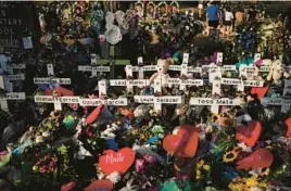  ?? JAE C. HONG/AP ?? Flowers are piled around crosses with the names of the victims in a school shooting as people visit a memorial May 31, 2022, at Robb Elementary School in Uvalde, Texas.