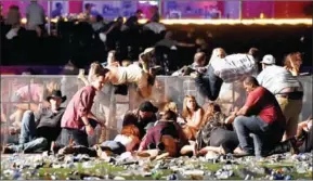  ?? DAVID BECKER/GETTY IMAGES/AFP ?? People scramble for shelter at the Route 91 Harvest country music festival after apparent gun fire was heard on Sunday in Las Vegas, Nevada.