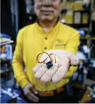  ??  ?? Lee holds a mini camera unit capabale of being built into custom-made devices, at his store in a market in Seoul.