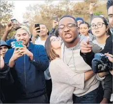  ??  ?? DORRIEN MATKINS, a freshman at Cal State Fullerton, is held back by a friend during an argument before the Yiannopoul­os event.