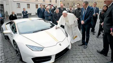  ??  ?? Lamborghin­i chief executive Stefano Domenicali watches as the Pope vandalises a parked car. Actually, he’s more than doubling its value.