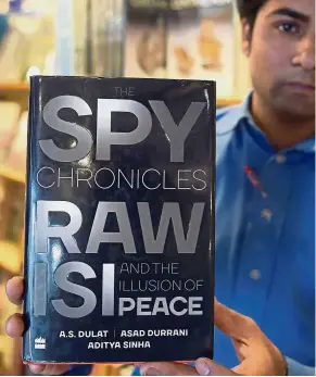  ??  ?? Page turner: A Pakistani bookstore employee displaying a copy of the book in Islamabad. — AFP