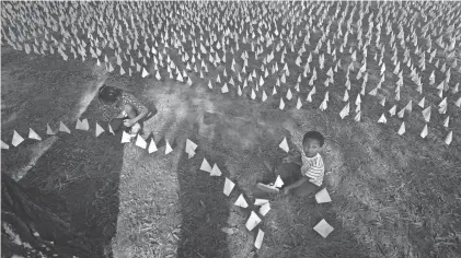  ?? JACK GRUBER/USA TODAY ?? Children helping to place white flags among an art project that opened to the public in Washington, D.C., to honor those who have died of COVID-19.