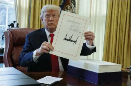  ?? EVAN VUCCI — THE ASSOCIATED PRESS ?? President Donald Trump shows off the tax bill after signing it in the Oval Office of the White House, Friday in Washington.