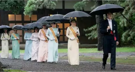  ??  ?? La llovizna amenazó con opacar los tradiciona­les actos. Pero el príncipe Akishimo encabezó la marcha al palacio seguido por su esposa Kiko y otras princesas. El hermano del Emperador, que no tuvo un hijo, sería heredero al trono.