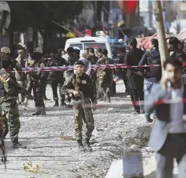  ?? AP PHOTOS ?? DEADLY ATTACK: Security forces, above, inspect the site of a suicide attack outside a Shiite mosque in Kabul. An Afghan policeman stands guard, below.