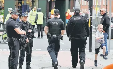  ??  ?? Armed police officers stand on duty as a boy taking part in a fun run skips past them, in central Manchester. — Reuters photo