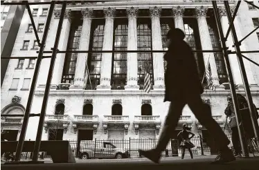  ?? Spencer Platt / Getty Images ?? People pass the New York Stock Exchange on Thursday. Even as the U.S. economy shrank 3.5 percent last year, the stock market managed to rise sharply, with the S&P 500 index gaining 16 percent.