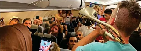  ??  ?? Brassed off: Musicians try to cheer passengers stuck on their flight as, top, families sleep on terminal floor