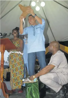  ??  ?? Prime Minister Andrew Holness showing the audience a piece of yellow yam which was among some of the items he received, following his presentati­on at Accompong.