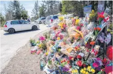  ?? SALTWIRE NETWORK ?? RCMP officers speak with a visitor near the large memorial in memory of the victims from the mass shooting seen at Portapique Beach Road in Portapique on April 30.