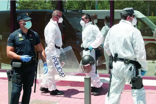  ?? EUROPA PRESS ?? Un grupo de policías nacionales con EPIs custodia a un grupo de infectados por Covid-19 en un centro de Cruz Roja de Málaga