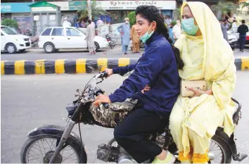  ?? Online ?? Women on a motorcycle make their way at a market place in Karachi. Prime Minister Imran Khan has urged the people to strictly follow precaution­s to prevent the alarming spread of Covid-19.