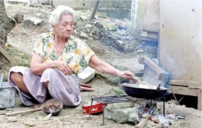  ?? PhotograPh by analy labor for the daily tribune ?? With prices of oil still on the rise, an elderly woman cooks food the traditiona­l way with firewood in Camarin, Caloocan City on tuesday.