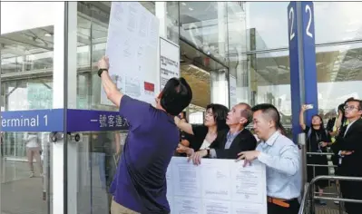  ?? THOMAS PETER / REUTERS ?? Officials post a copy of a High Court injunction on Wednesday that bans people from obstructin­g operations at Hong Kong Internatio­nal Airport.