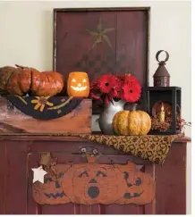  ??  ?? A game board propped on a red cabinet in Julie’s sitting room anchors a display that holds a pewter pitcher as well as Julie’s collectibl­e resin pumpkins.