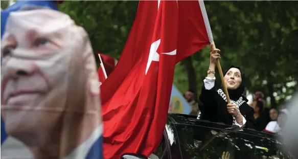  ?? AP ?? A supporter of the President Recep Tayyip Erdogan waves a Turkish flag outside the AKP offices in Istanbul. Mr Erdogan was set to be re-elected last night